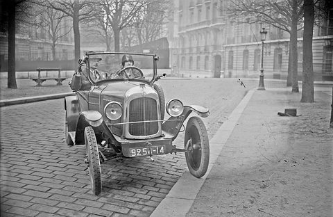 Front view of a small open car with a flat radiator, two headlamps and plate 9251-I4, an instructor and a pupil aboard.