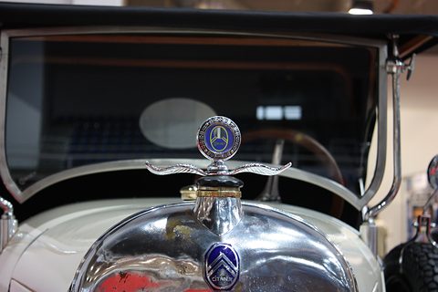 A chrome winged radiator cap with a blue Citroën gauge above a chrome radiator shell and chevron badge. Opens a larger view
