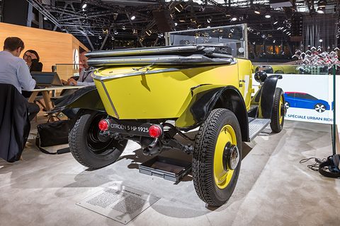 Rear three-quarter view of a yellow car with a pointed tail, red rear lamps and its hood folded. Opens a larger view