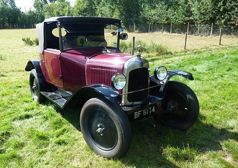A maroon cabriolet with a black roof and side windows and plate BF 6174 standing in a grassy field. Opens a larger view