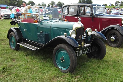 A dark green open tourer with green wheels, a toolbox on the running board and plate BF 4547, on grass. Opens a larger view