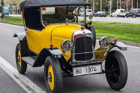 A yellow car with a black hood and plate BU-1974 parked at the edge of a city avenue. Opens a larger view