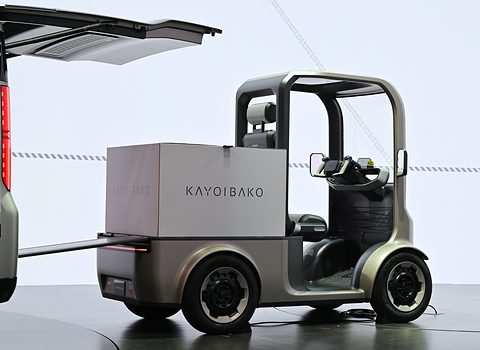 Grey open single-seat concept with a large KAYOIBAKO cargo box on its rear deck against a white backdrop. Opens a larger view