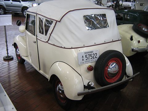 White small car from the rear, a spare wheel on the tail, a Tennessee plate and a fabric top with a small window. Opens a larger view