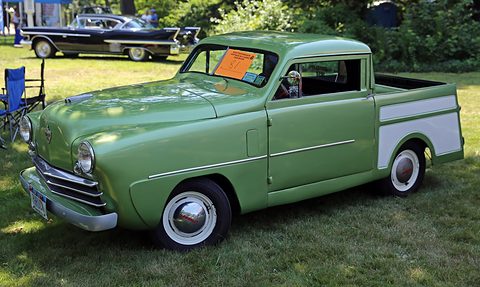 Green small pick-up with a white-painted bed side, whitewall tyres and a chrome grille, on grass. Opens a larger view