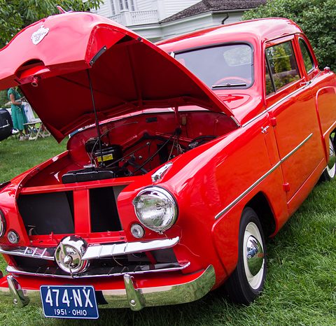 Red small saloon with its bonnet open, a spinner in the grille and an Ohio plate, on grass. Opens a larger view
