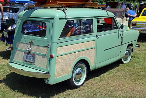 Turquoise small estate from the right rear with pale woodgrain panels, parked on grass at a show. Opens a larger view