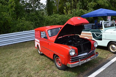 Red small estate with its bonnet open showing the engine, parked on grass by a crash barrier. Opens a larger view
