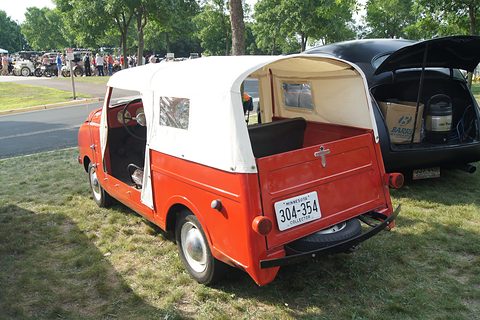 Red open utility from the right rear with a white soft top and a Minnesota plate. Opens a larger view