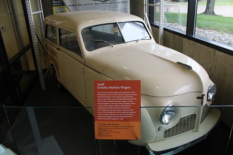 Cream small estate in a glass display case, a red information panel standing in front of its nose. Opens a larger view