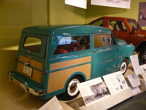 Teal small estate with woodgrain panels from the left rear, period photographs on panels beside it. Opens a larger view