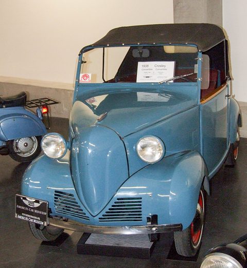 Light blue small two-door with a black fabric top, V-shaped nose and twin round headlamps, a museum card on the screen. Opens a larger view