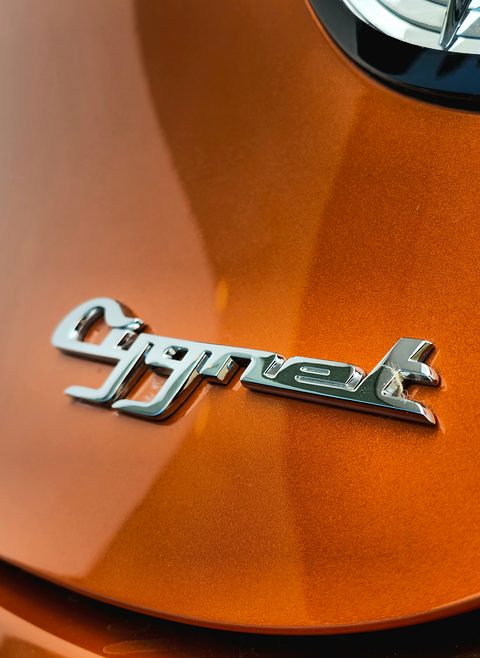 Close-up of a slanted chrome Cygnet script badge on glossy copper paintwork. Opens a larger view