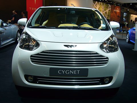 White city car facing the camera, a chrome slatted grille and a Cygnet name plate. Opens a larger view