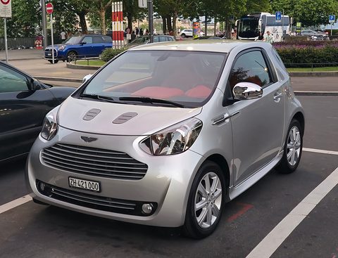 Silver city car with red seats visible through the windscreen, parked in a marked bay. Opens a larger view