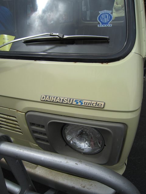Close view of a cream van nose with a chrome ‘55 Wide’ badge, a headlamp and a bull bar. Opens a larger view
