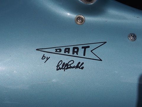 An arrow-shaped DART decal above the words ‘by Bill Buckle’ in a handwritten signature, on light blue paint.