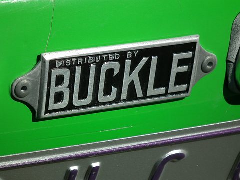 A chrome plate lettered DISTRIBUTED BY BUCKLE fixed to bright green paint. Opens a larger view