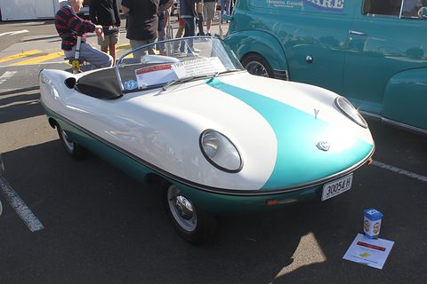 White roadster with a teal flash on its nose and a display card on the ground in front. Opens a larger view