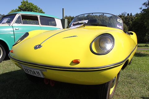 A yellow roadster seen from the front, its round headlamps set deep in the curved wings. Opens a larger view