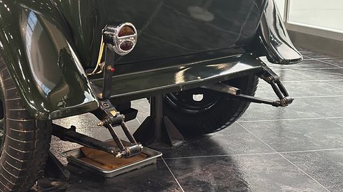 Close view under the side of a dark green car: a step plate on brackets, the front wing and a wheel. Opens a larger view