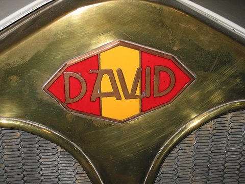 An elongated red, yellow and red enamel badge reading David on a brass radiator shell above the honeycomb core.