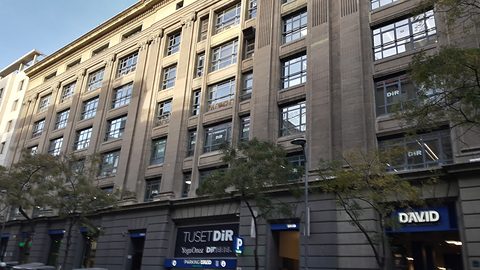A tall stone-faced office building with long window bands and a blue David sign over a street-level entrance.