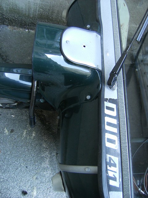 Chrome DUO 4/1 lettering on a dark green panel beside an open door, a grey pavement below. Opens a larger view