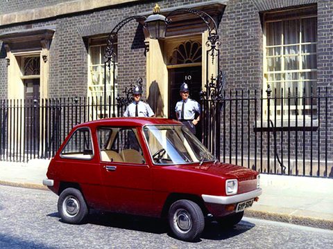 Small red car parked before a black door guarded by two police officers.