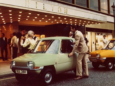 Pale green car at a hotel entrance at night, a man opening its door and people watching. Opens a larger view