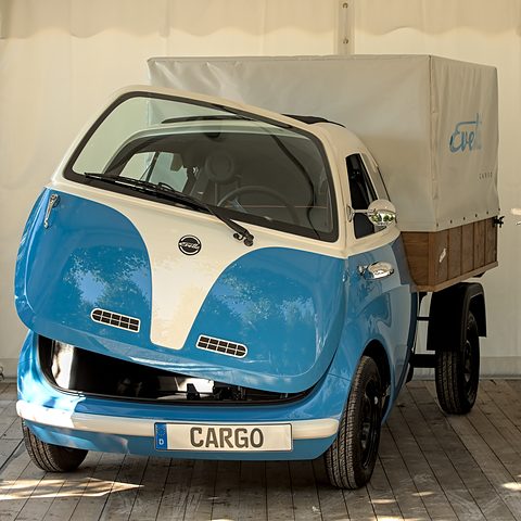 Blue and white bubble cab with a short pick-up bed under a grey canvas cover and a CARGO plate. Opens a larger view