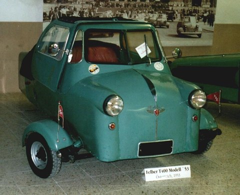 Green three-wheeled cabin scooter with a fabric roof, a card reading Felber T400 Modell 53 in front.