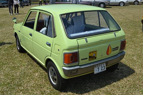 Rear three-quarter of a lime-green hatchback with red tail lamps, on grass. Opens a larger view