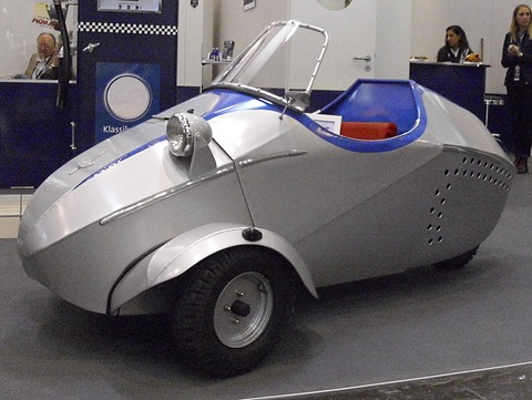 Silver and blue open three-wheeler with a red seat cushion, a hoop windscreen and holes along the tail.