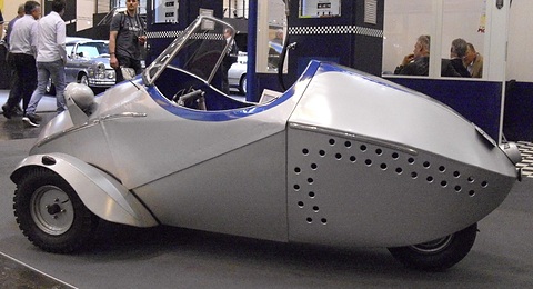 A small silver and blue open three-wheeler in profile, with a pointed nose and long tapering tail. Opens a larger view