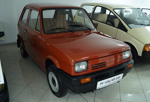 Orange small hatchback with a black bumper, rectangular headlamps and a ‘PF 126p NP-650’ plate on a tiled floor. Opens a larger view