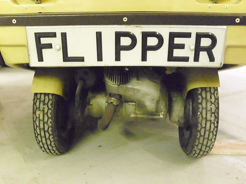 Low view under a FLIPPER number plate: two small treaded front wheels close together with a finned engine between them.
