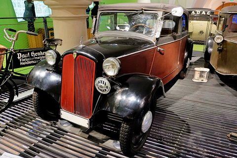 Small two-tone saloon with a red dummy radiator, black wings and round lamps on a slatted display floor. Opens a larger view