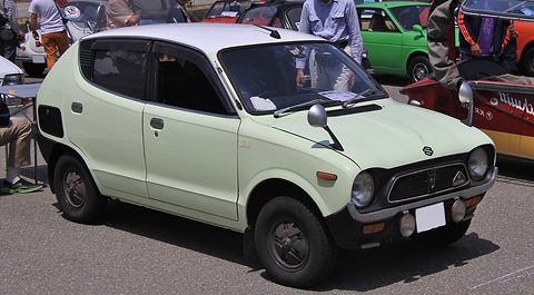 Pale green small hatchback-shaped saloon with a white roof and black grille, visitors behind. Opens a larger view