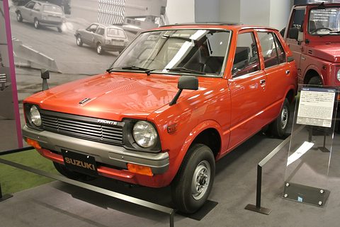 Orange small five-door car on a grey floor, an information stand beside it. Opens a larger view