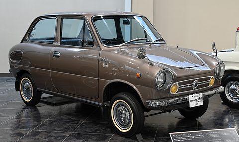 Bronze small saloon with whitewall tyres on a dark polished floor against a beige wall.