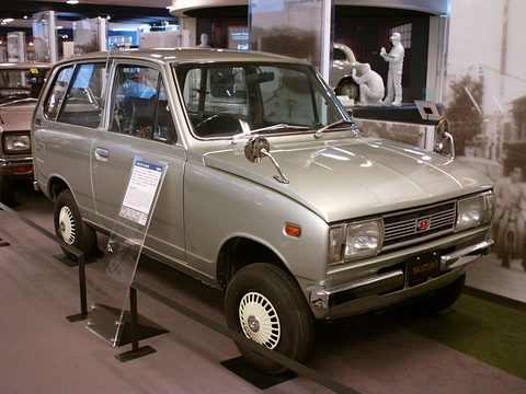 Silver small estate van on a dark floor, an information stand by its wing. Opens a larger view