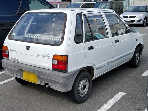 Rear three-quarter of a white five-door car with large tail lamps, in a car park. Opens a larger view