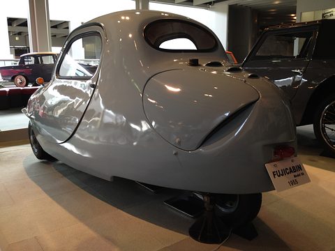 Rear view of a rounded pale grey three-wheeler with a large engine lid, a small rear wheel and a FUJICABIN plate.