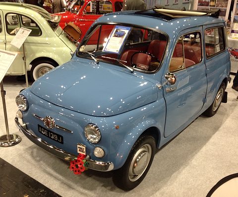 Pale blue small estate car on a show stand with an open sunroof, other small cars behind. Opens a larger view