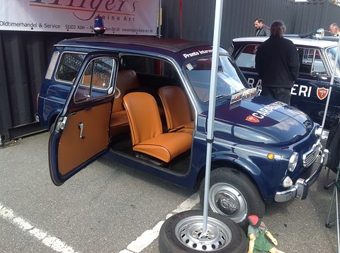 Dark blue small estate car with an open rear-hinged door showing tan seats, under a gazebo. Opens a larger view
