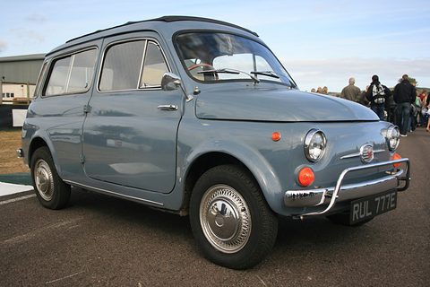 Grey small estate car with a chrome nudge bar and spotlamp parked on tarmac under a blue sky. Opens a larger view