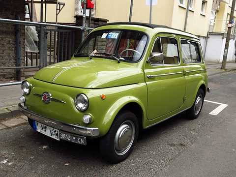 Lime-green small estate car with chrome bumpers parked in a marked bay on a town street. Opens a larger view