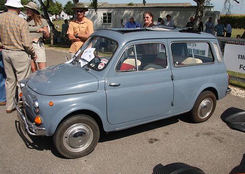 Grey small estate car parked in sunshine, people in summer clothes standing beside it. Opens a larger view