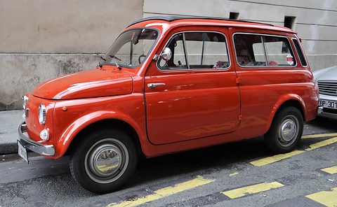 Side view of an orange small estate car with sliding rear windows parked by a wall. Opens a larger view